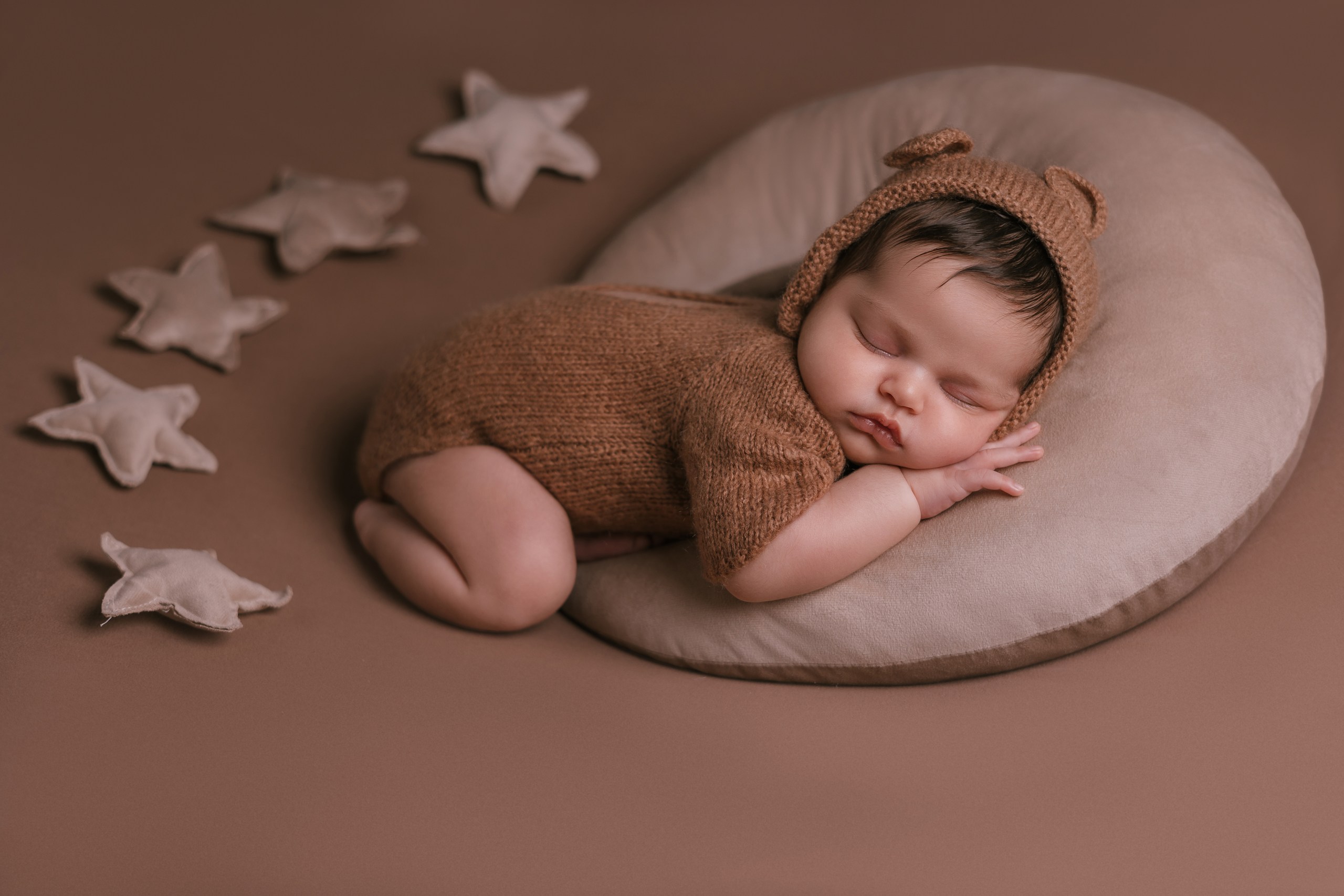 Sleeping baby curled in a crescent moon surrounded by stars