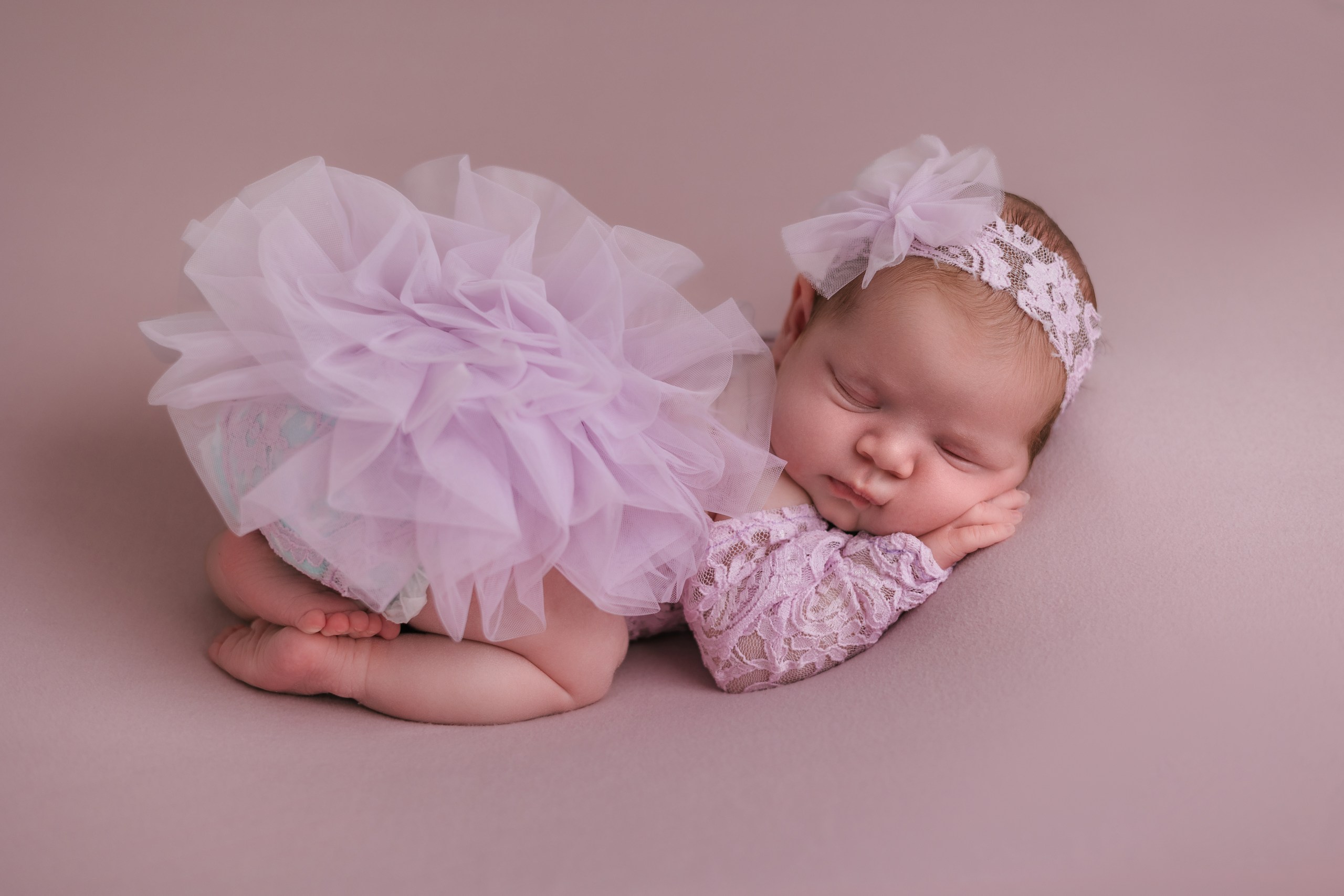 Newborn in a lilac tutu with a matching floral headband