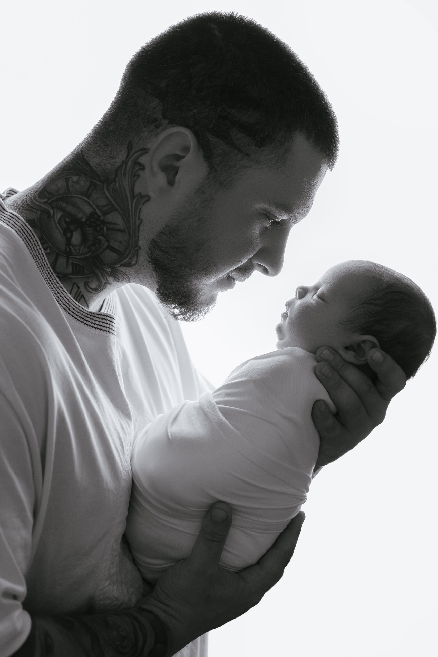Black-and-white portrait of a father holding his newborn