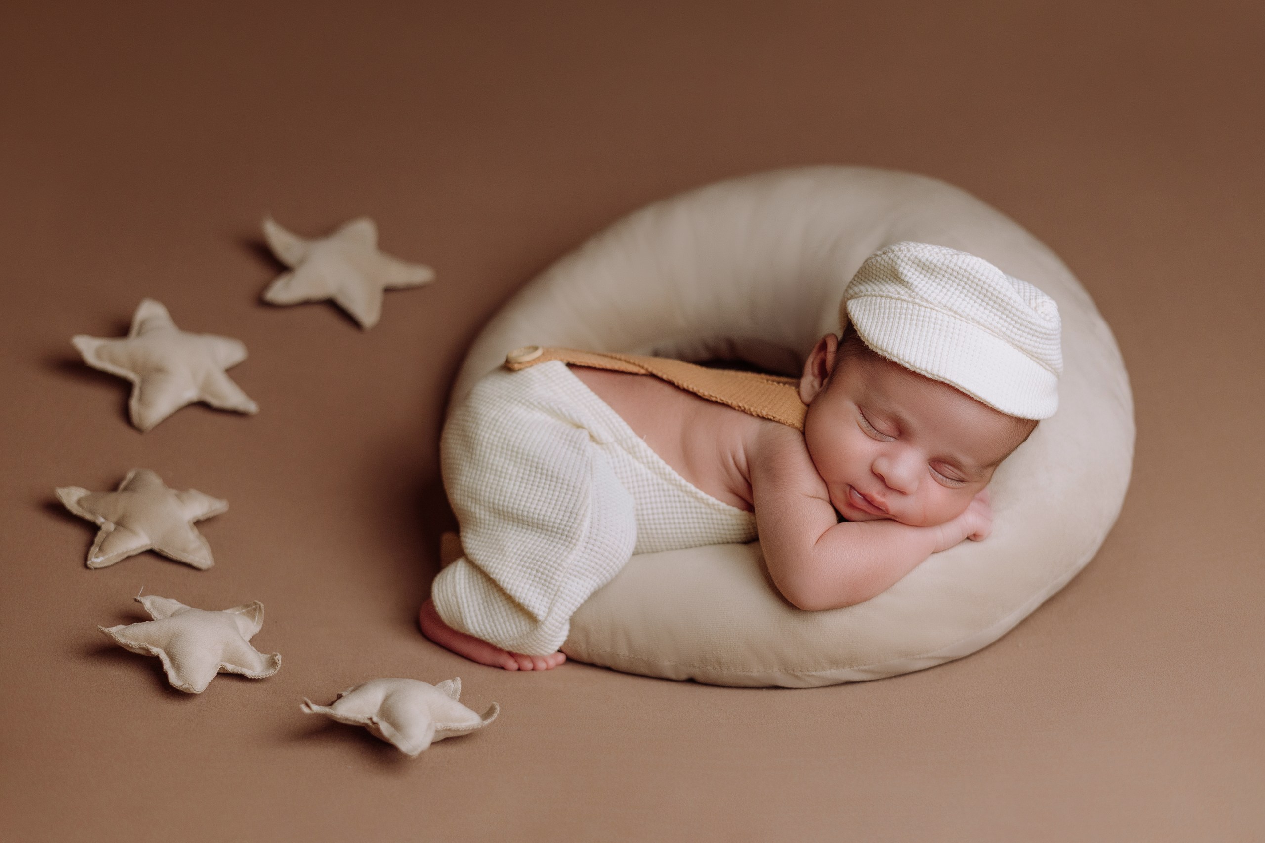 Baby in a cream wrap nestled in a moon-and-stars setup